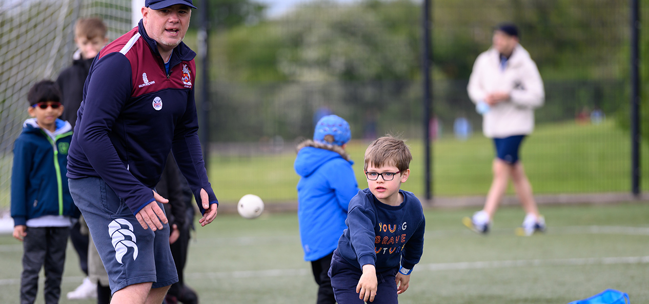 A man coaches a young boy as he throws a ball