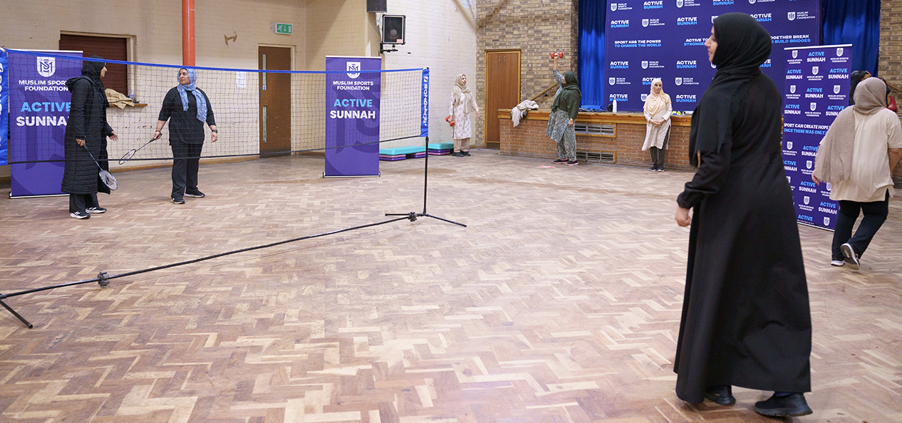 A group of women wearing veils play indoors badminton.