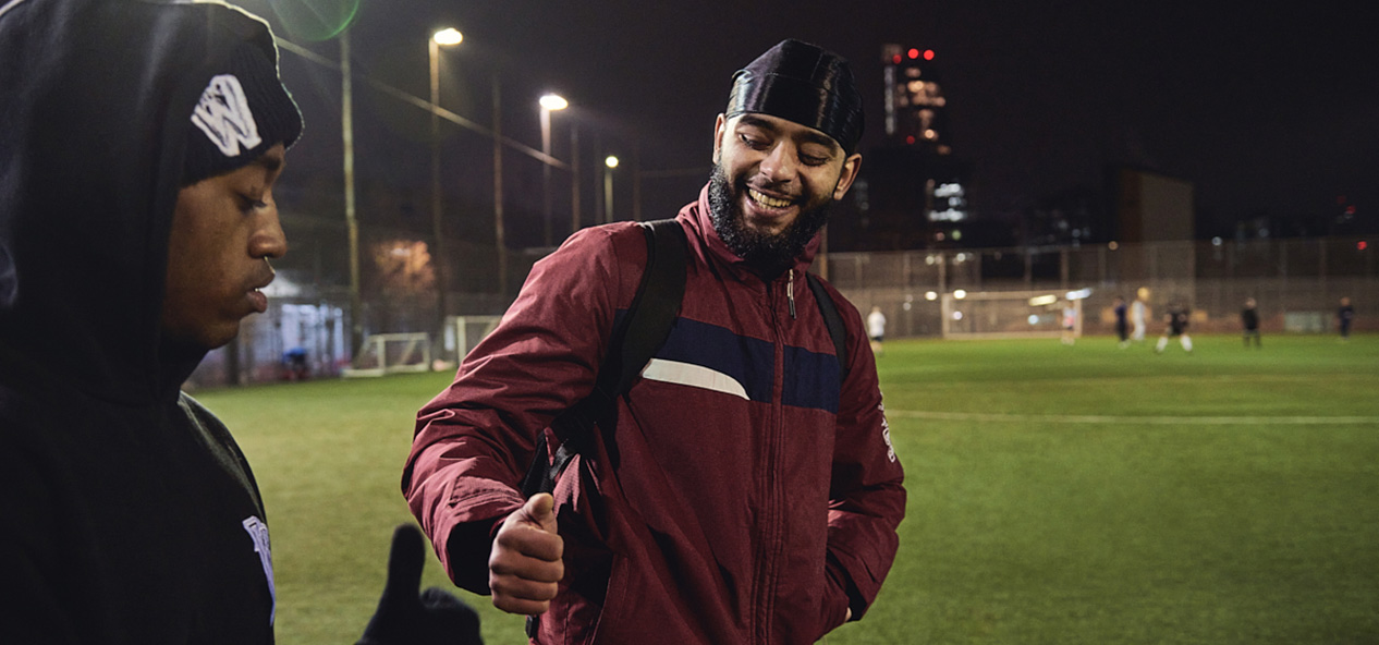 Two men fist-bump as they walk onto a 4G pitch to play football