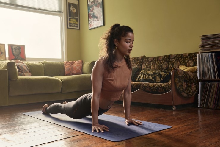 A woman stretches on a yoga mat in a room at home.