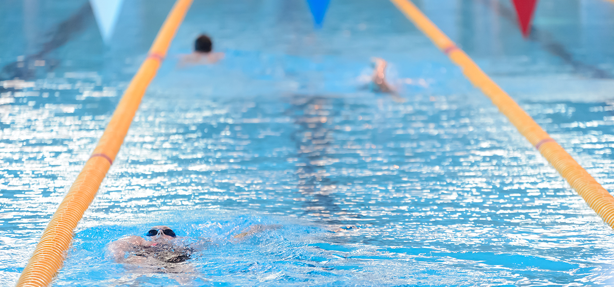 People swim in lanes in an indoor swimming pool