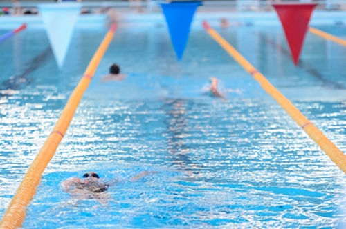 People swim in lanes in an indoor swimming pool