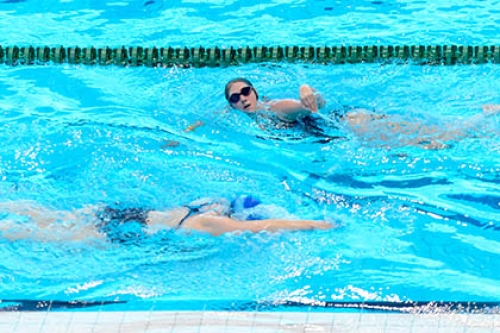 Two swimmers pass each other in a public pool 