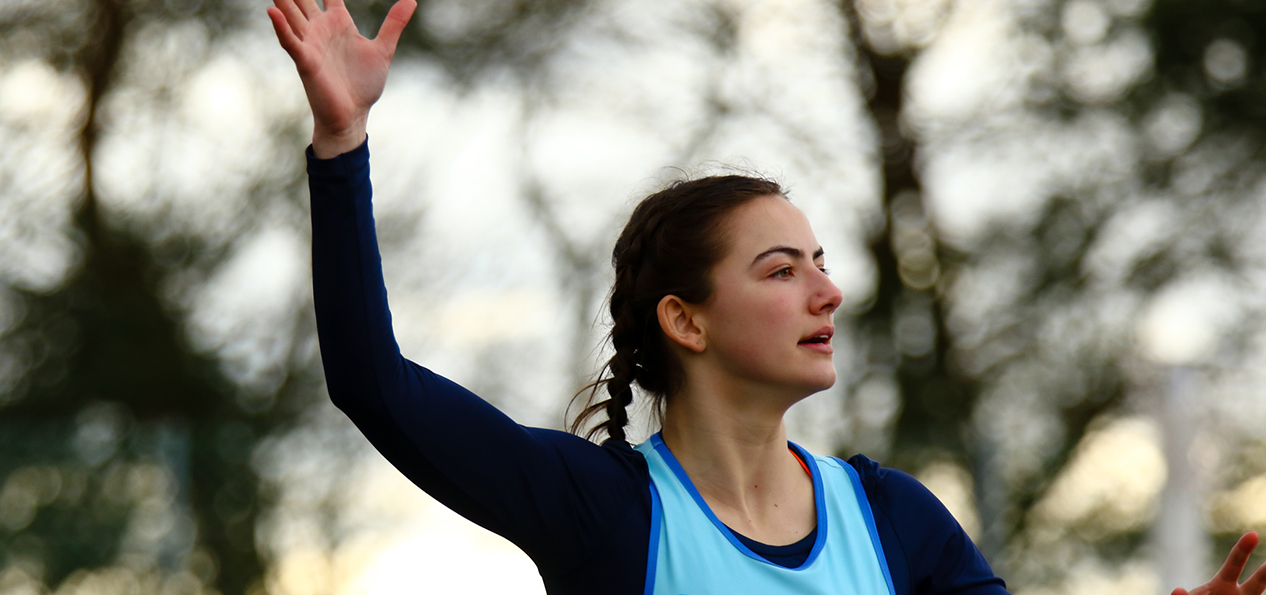 A girls calls for the ball while playing netball outside.