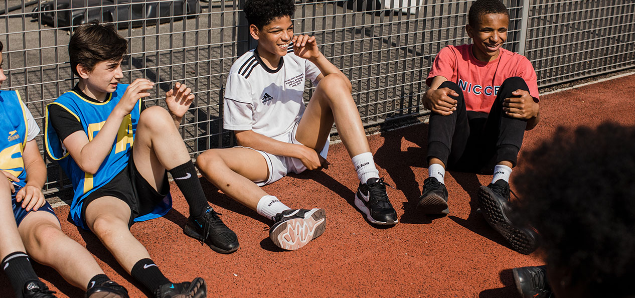 A group of kids relax while sitting on the floor outdoors