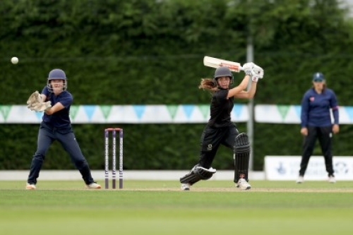 A batter hits a shot while the wicketkeeper looks on, during a girls' cricket game at the 2021 School Games National Finals at Loughborough University.