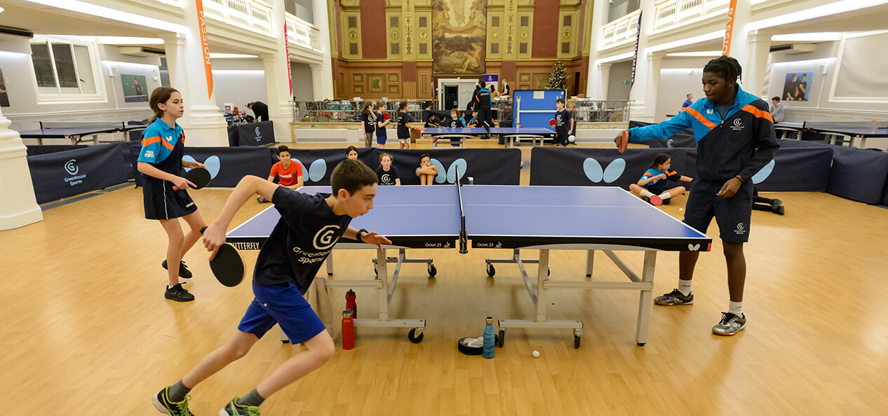 A boy runs around a table tennis table during a game.