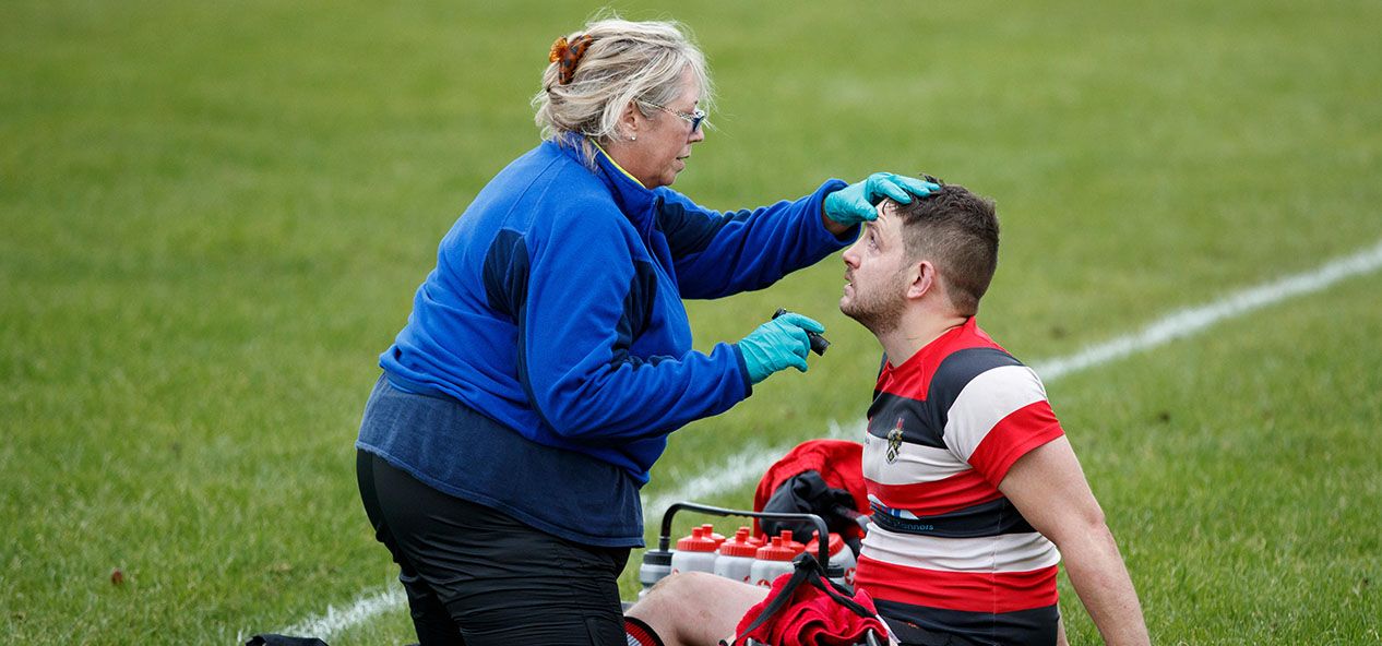 A medic tests a rugby player for concussion at the side of the pitch