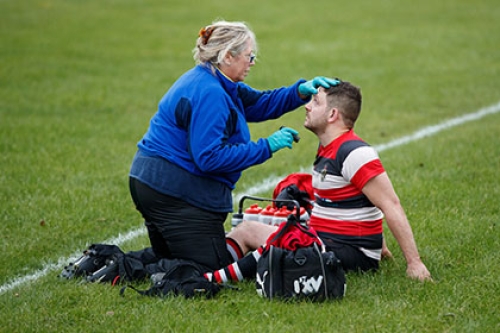 A medic tests a rugby player for concussion at the side of the pitch