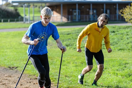 A Nordic walker with a coach running alongside