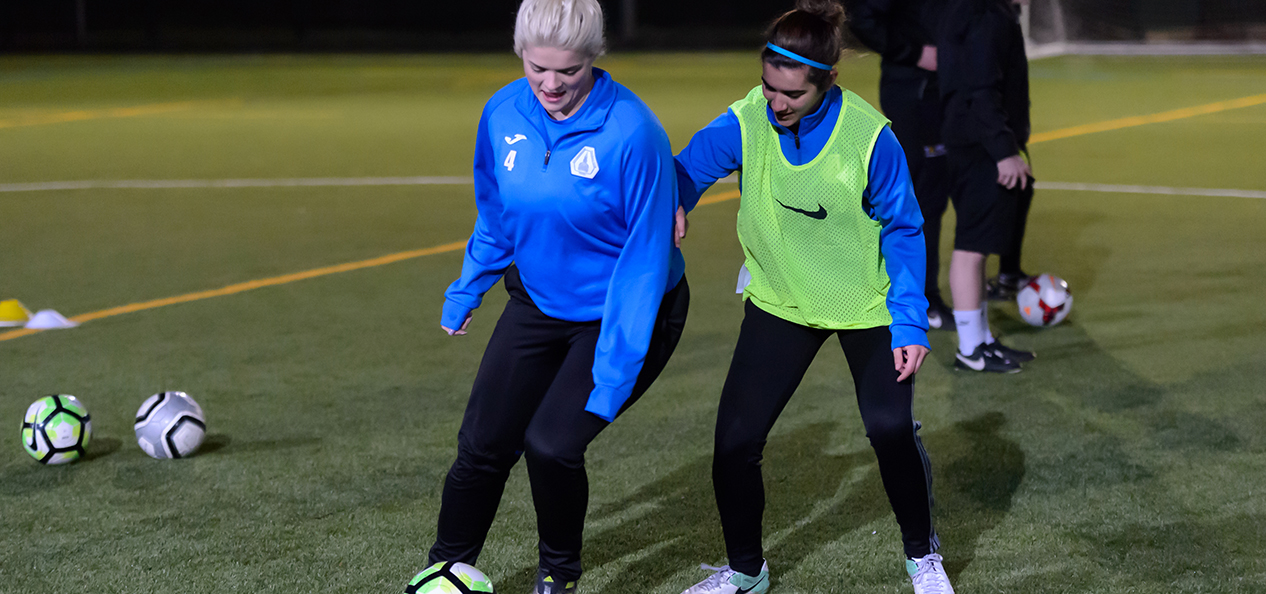 Two girls playing football on a 3G pitch