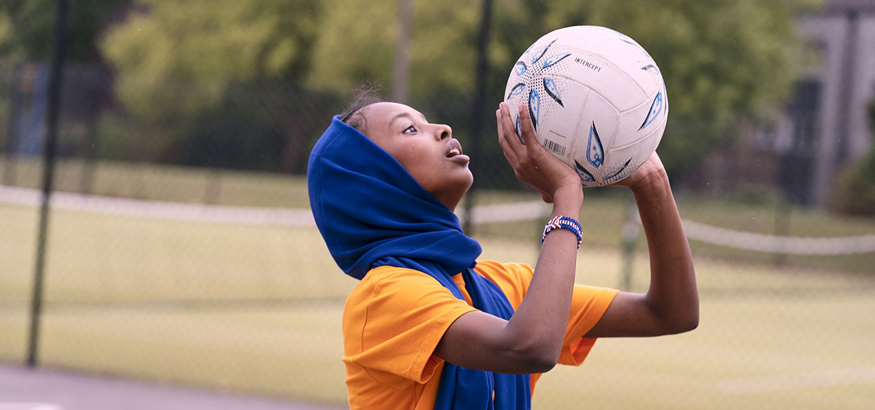 A girl prepares to take a shot while playing netball