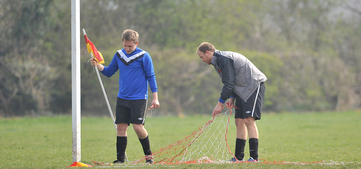 Players set up the nets and corner flags for a football match