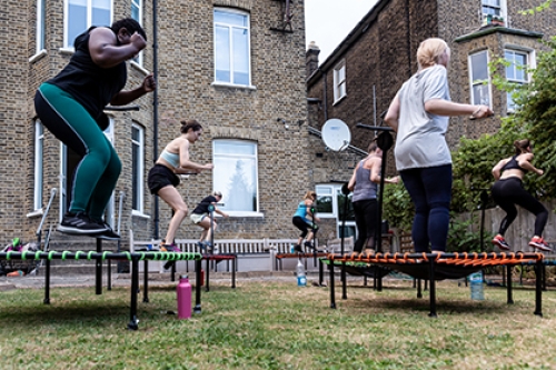 A group of women participate in a mini-tramp exercise class outdoors