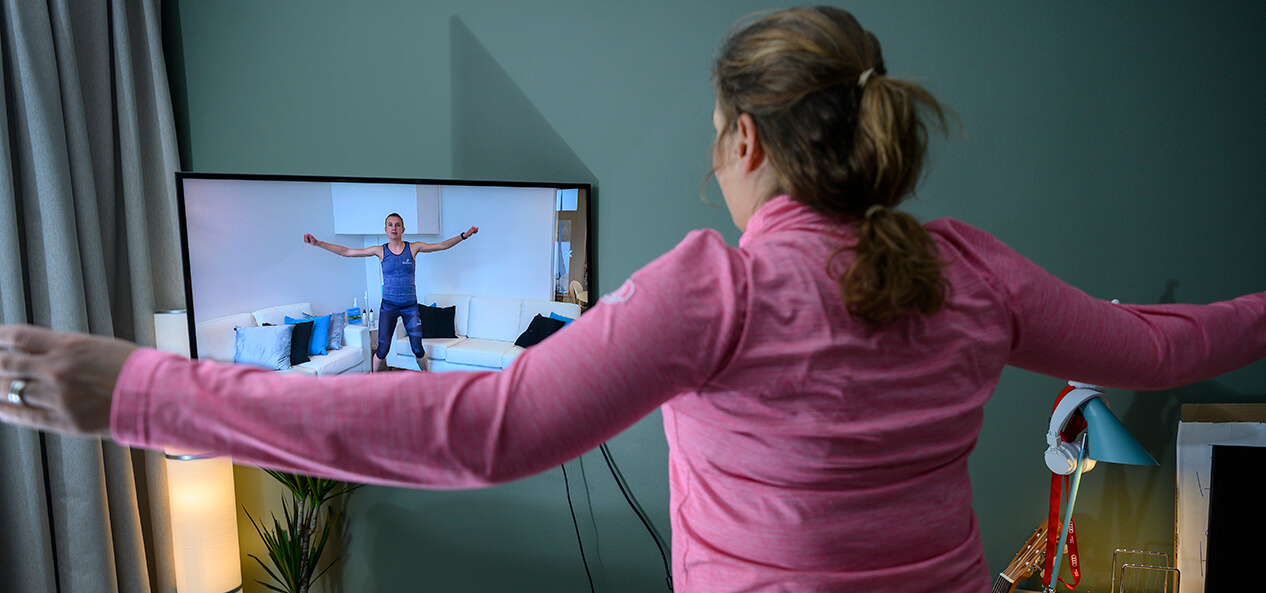 A woman following a home workout she's watching on her TV.