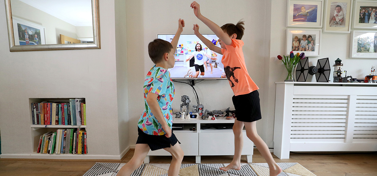 Two boys perform exercise in their living room as part of Joe Wicks' 'PE with Joe' programme.