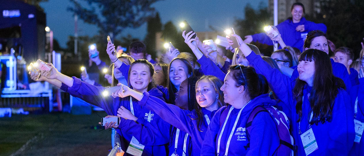 A group of School Games participants holding their mobile phones in the air with the torch lights on.