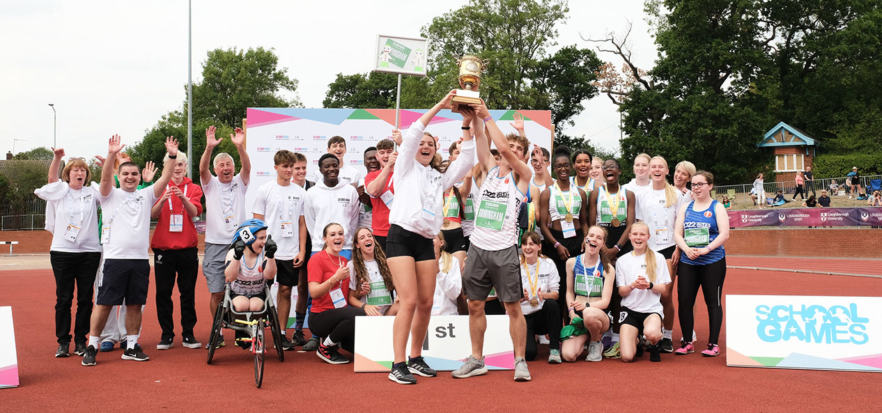 A group of athletes at the 2022 School Games National Finals celebrate and hold a trophy aloft