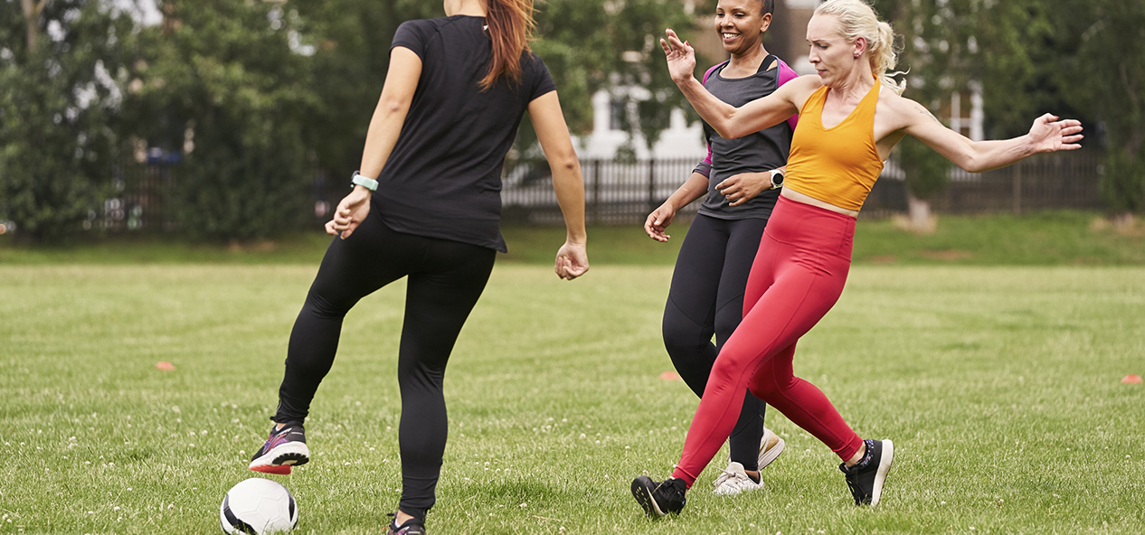 A group of women playing football in a park.