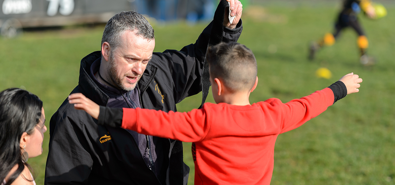 A coach puts tag rugby straps on a child