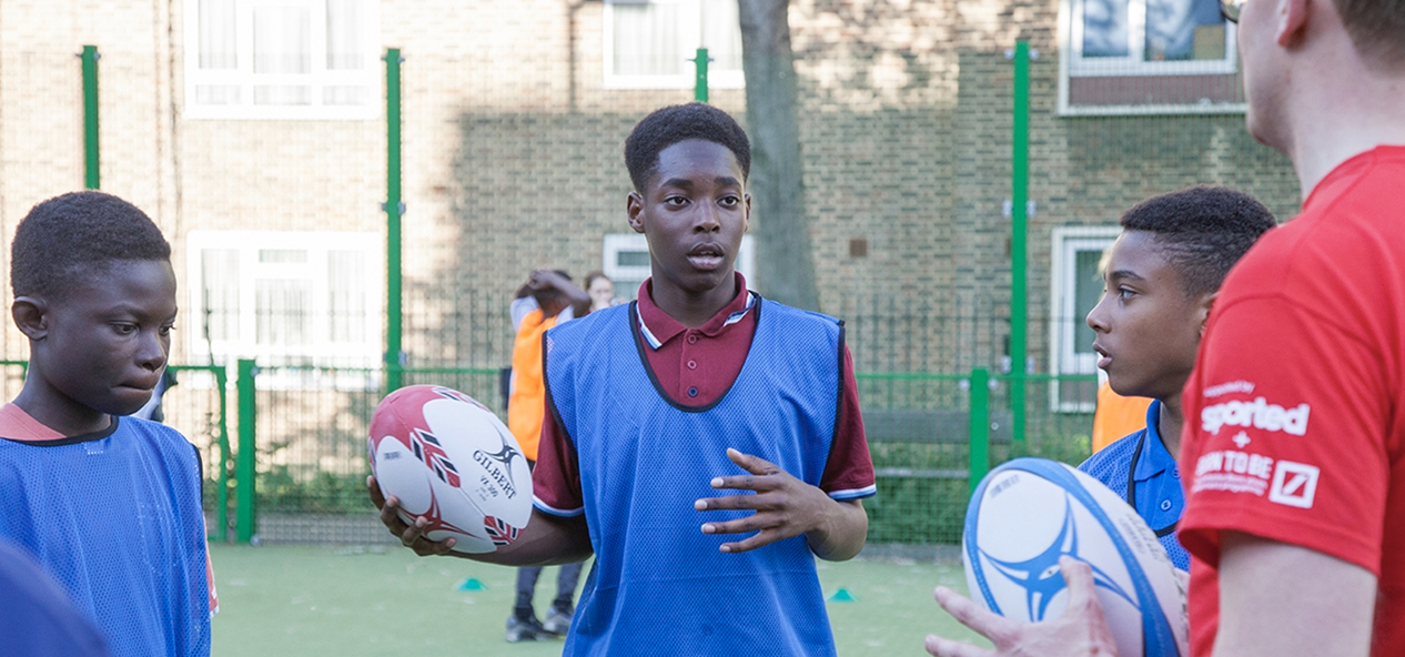 A member of Sportsed Foundation talks to some kids during a rugby session.