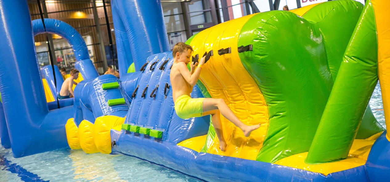 A boy plays on an inflatable obstacle course in a swimming pool