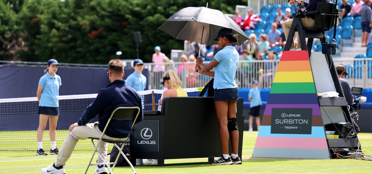 A shot of a grass-court tennis match at the Lexus Surbiton Trophy, with the umpire's chair decorated in the colours of the Pride rainbow