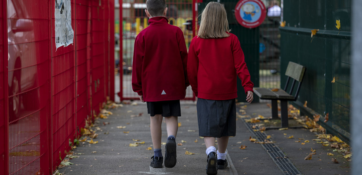 A boy and a girl walk side by side towards their school.