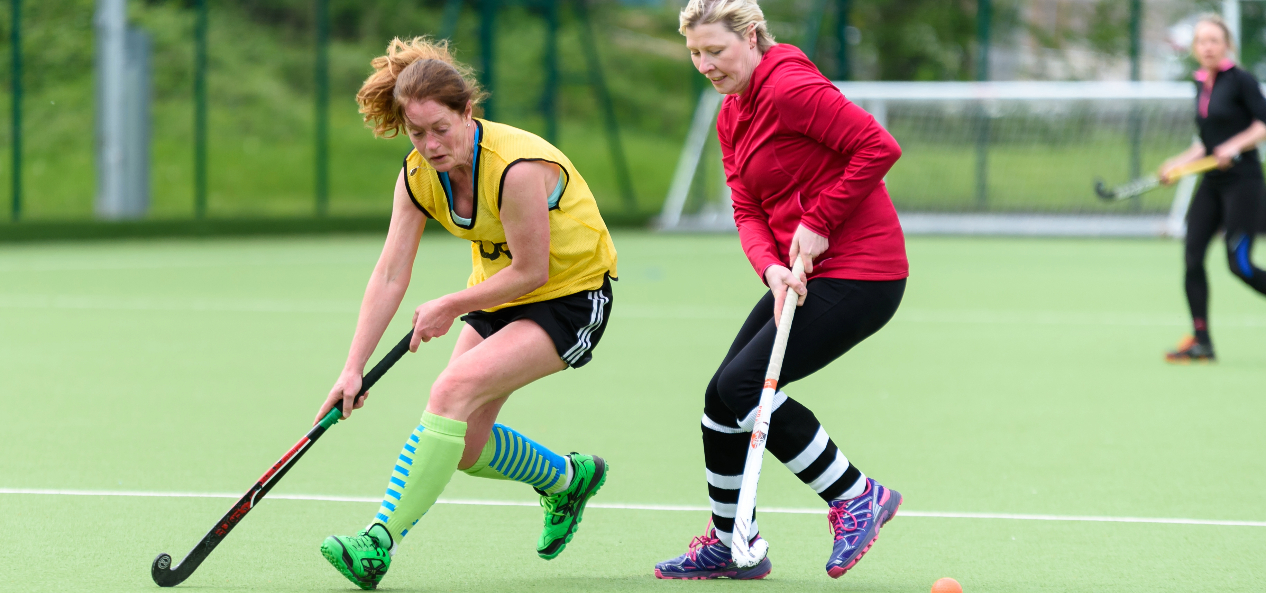 Women playing hockey outdoors