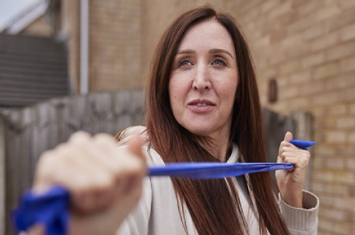 A woman exercising with a resistance band in her garden