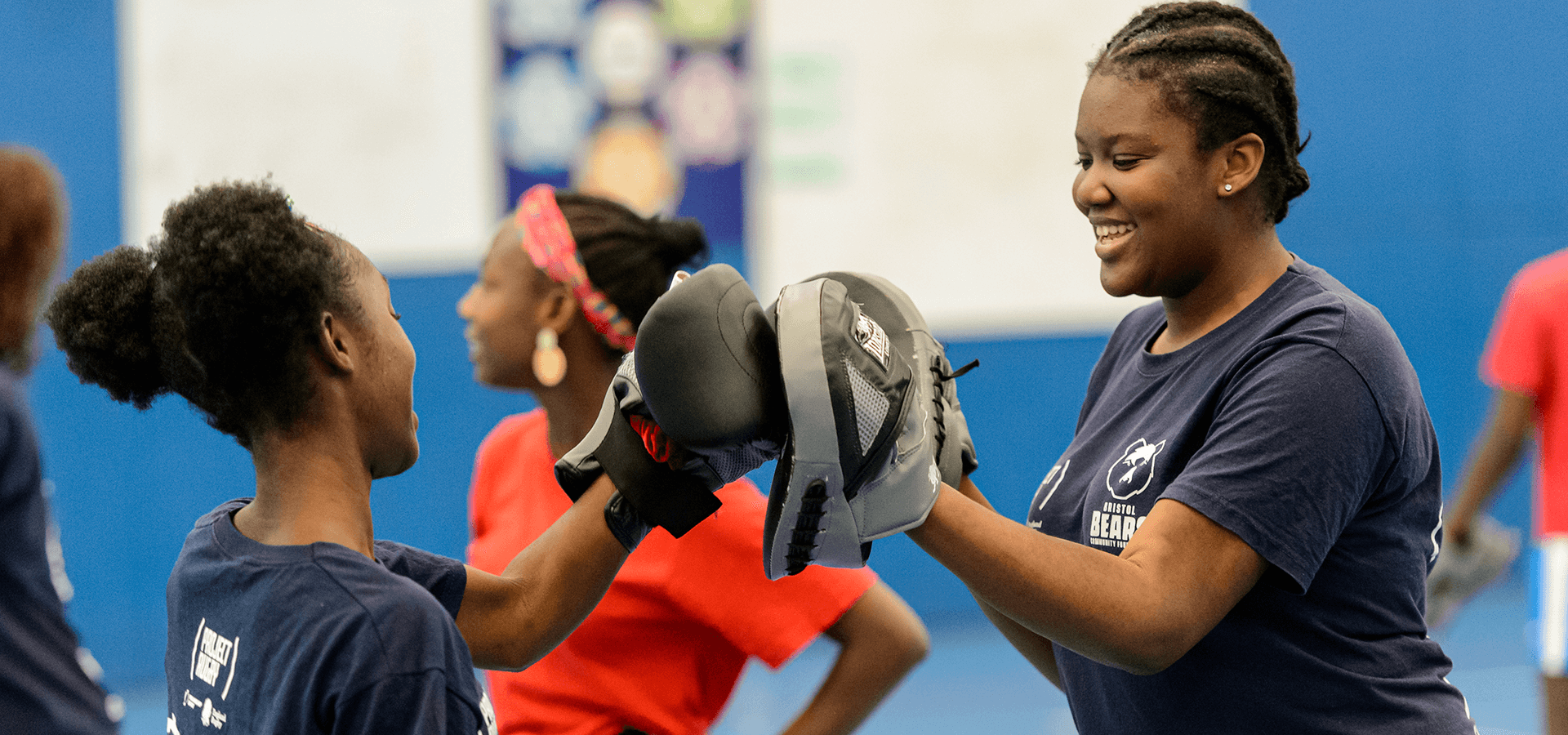 Boxing coach helping girl using pads