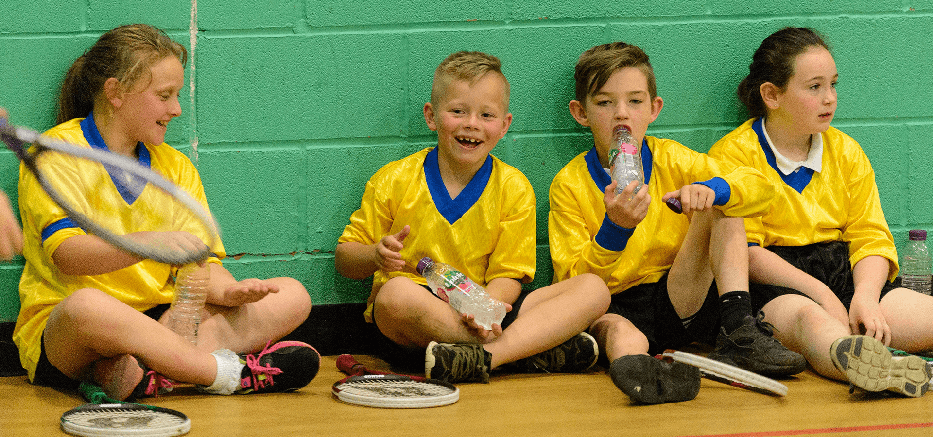 Four children resting during tennis practice