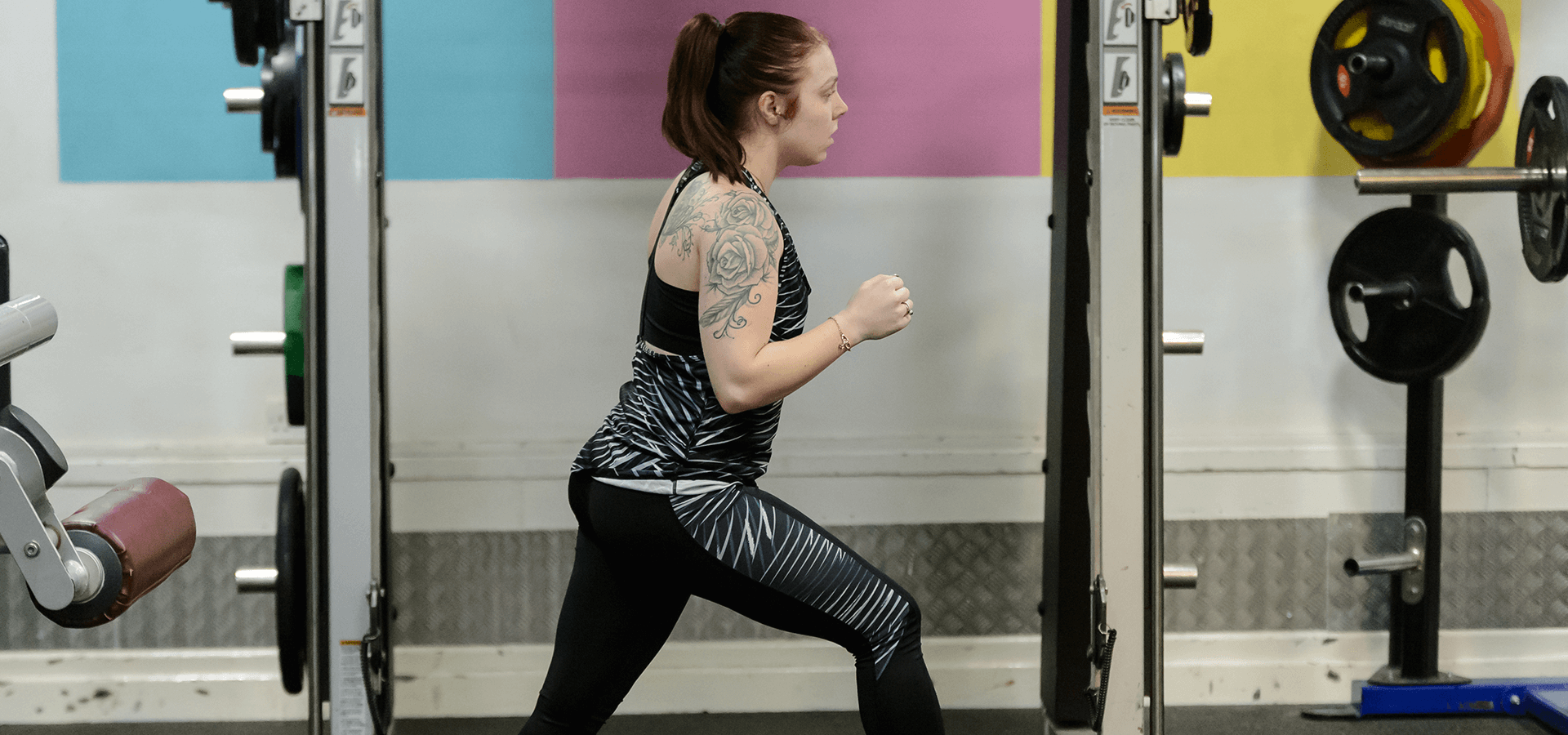 Girl working out in gym in front of weights rack