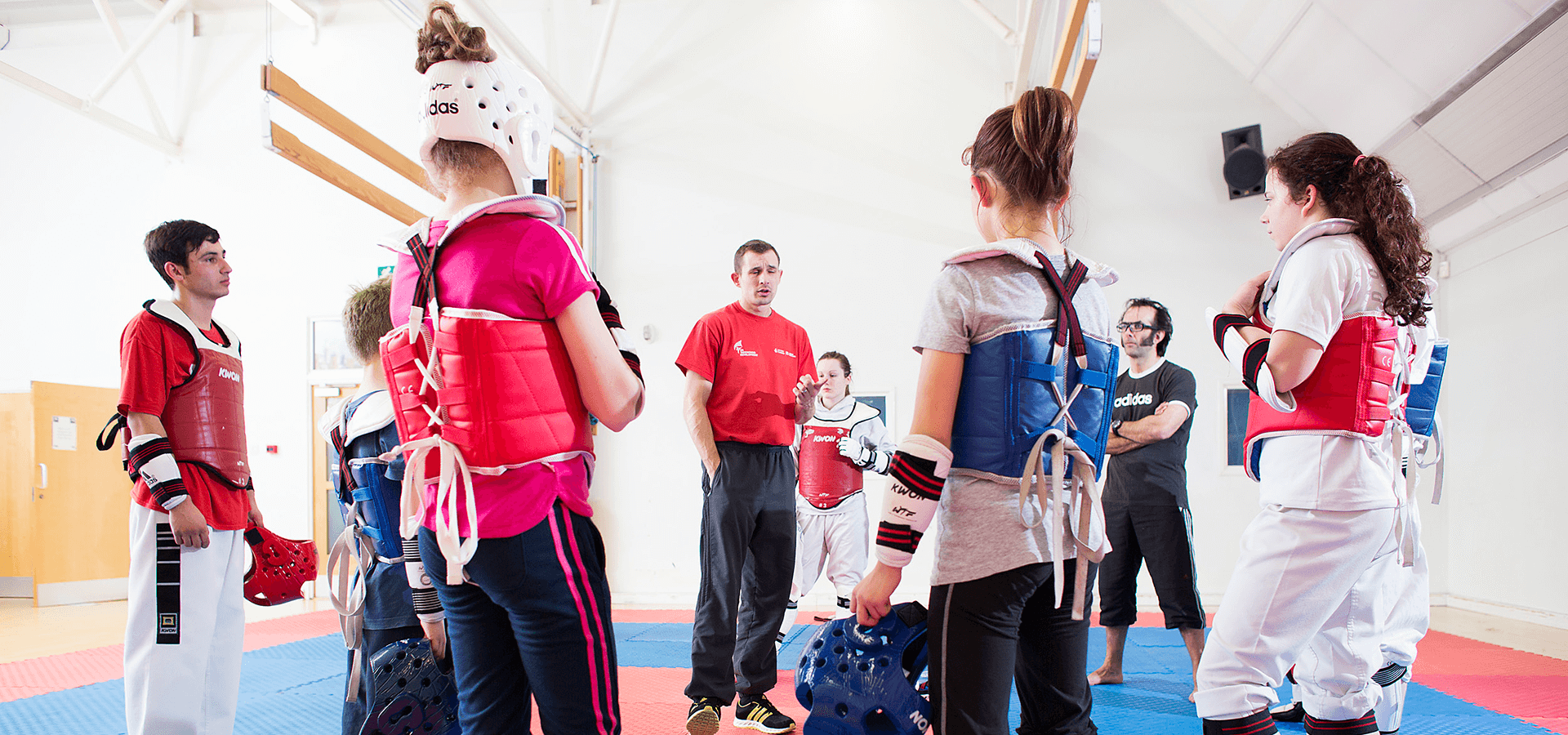 Young adults listening to coach during taekwondo class