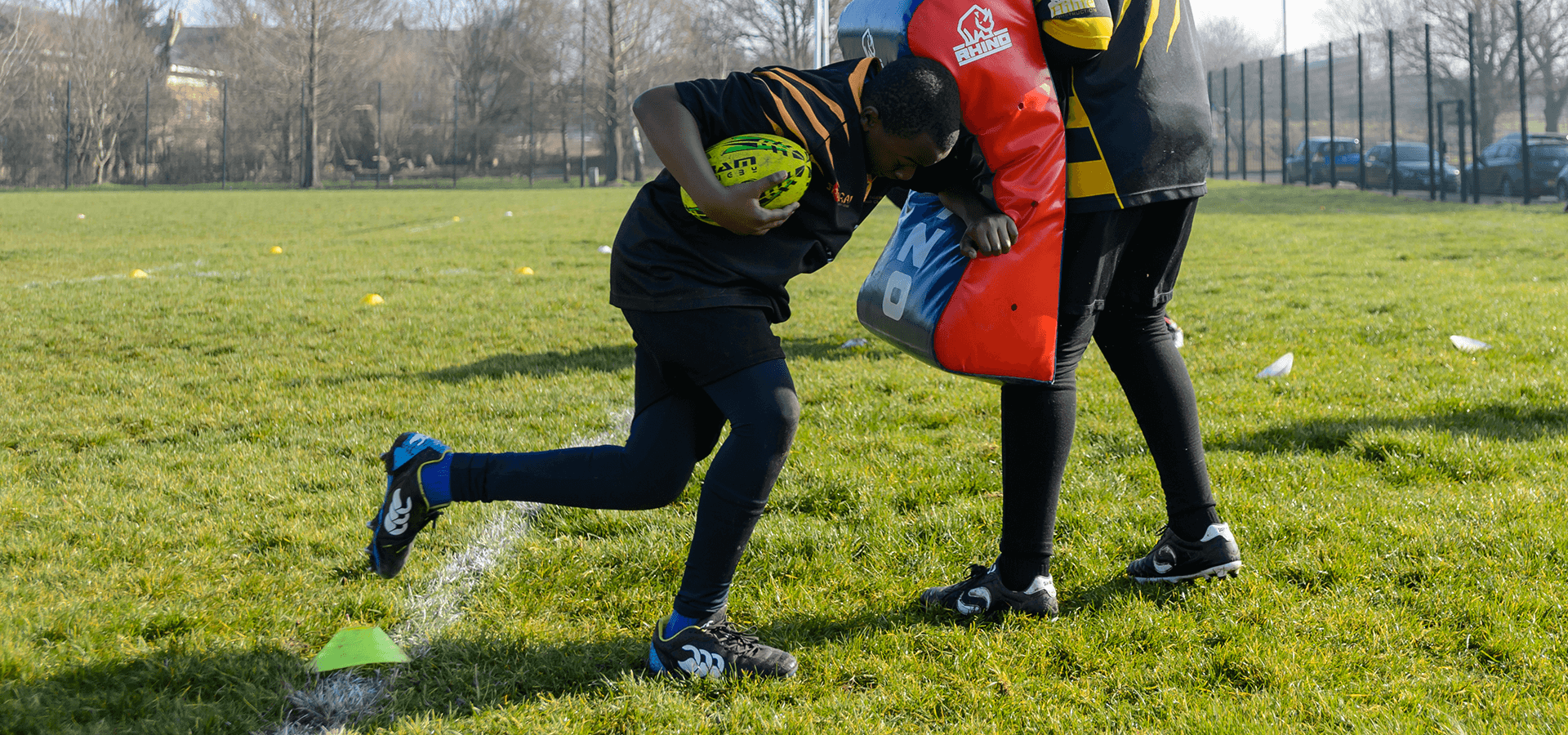 Young boy practicing american football tackle using cushion