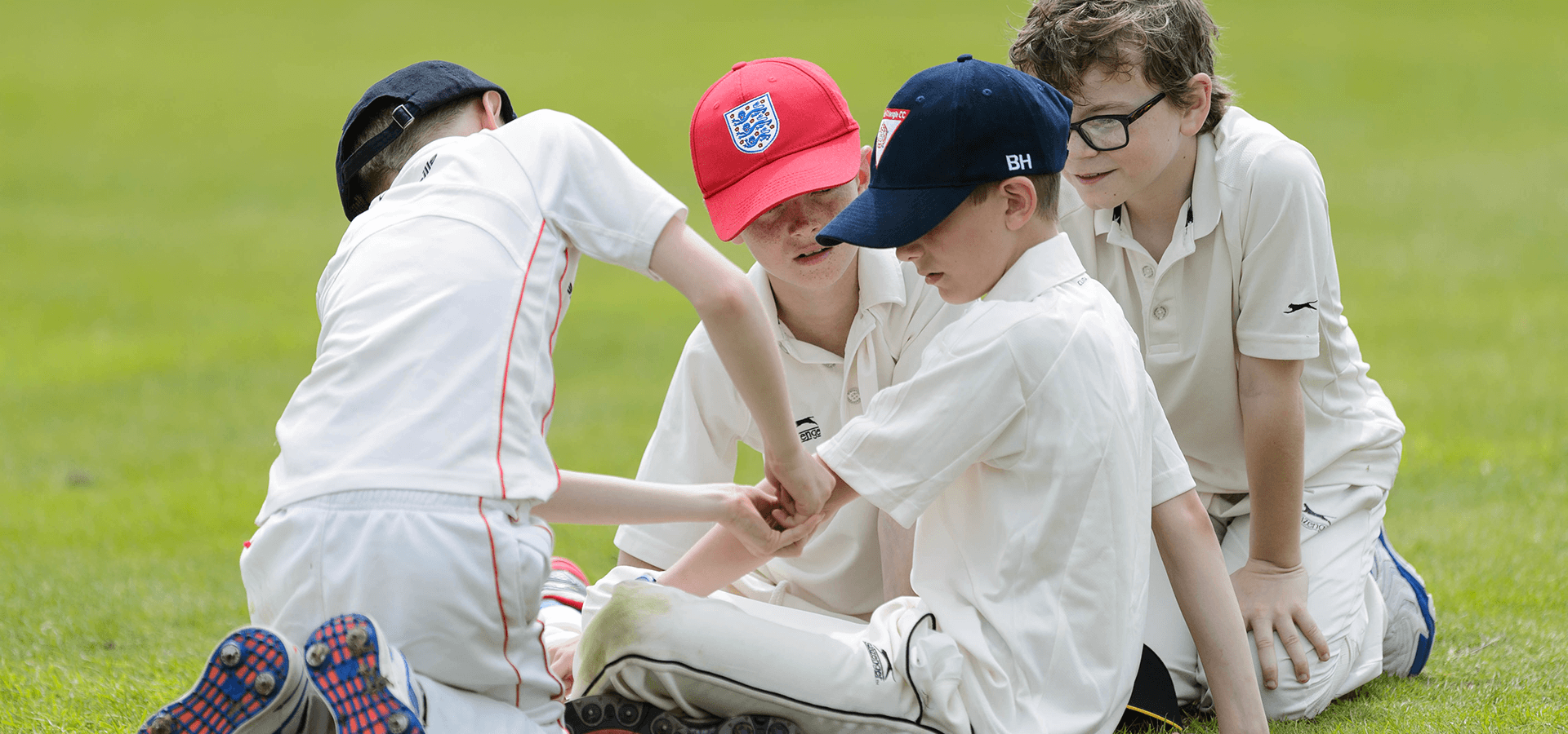 Young boys helping each other during cricket