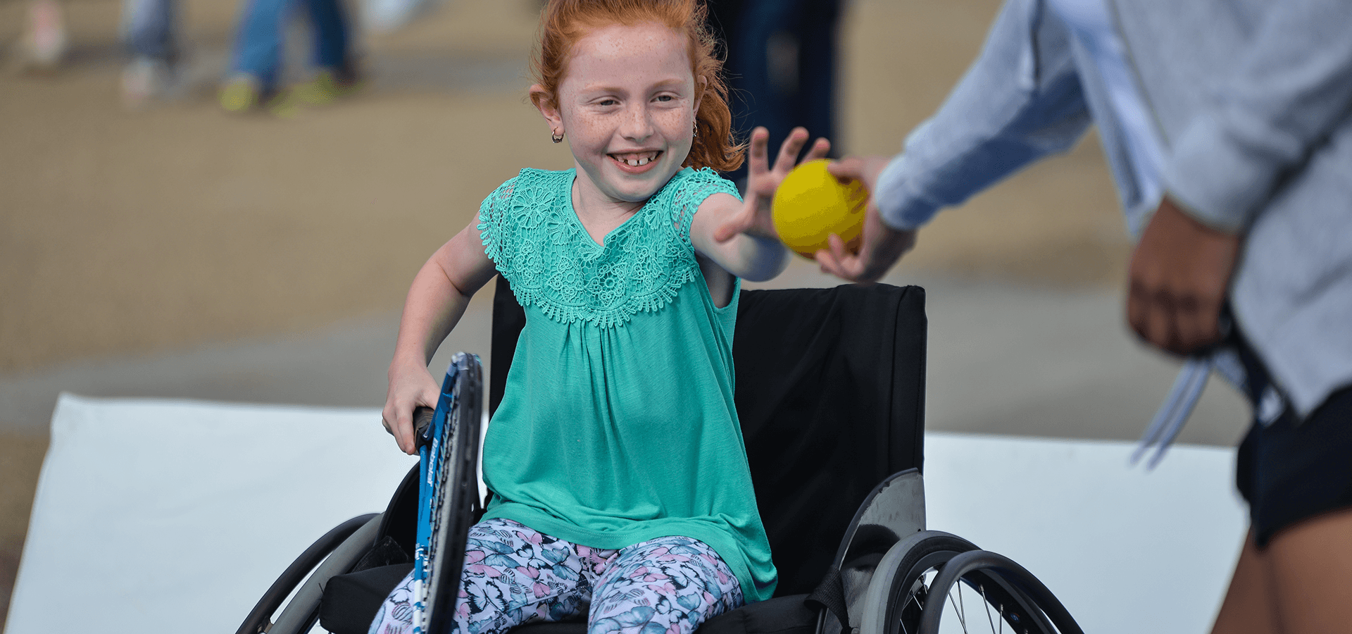 Young girl in wheelchair receiving ball