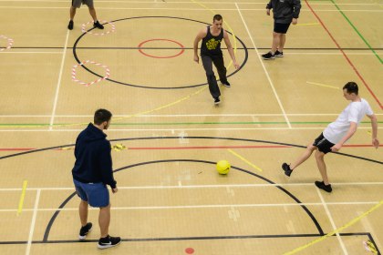 Young men playing football in sports hall