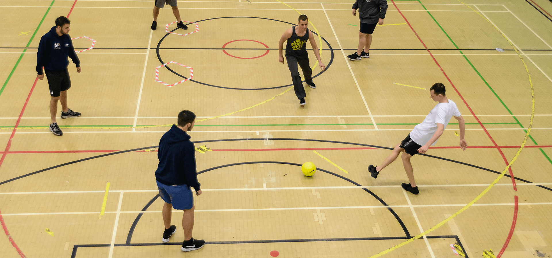 Young men playing football in sports hall